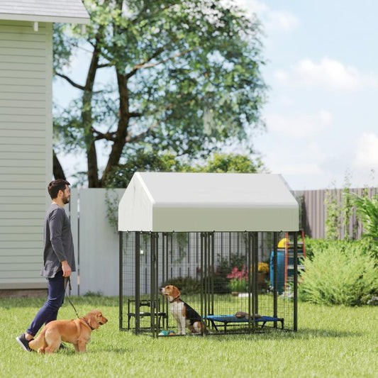 Outdoor dog kennel with peaked roof and welded wire panels in backyard grass, with two dogs.