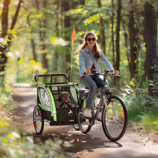 Green and black double child bike trailer attached to a bicycle, front and side view