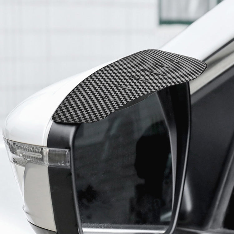 Car side mirror rain shield cover installed, carbon fiber check pattern on the top edge.