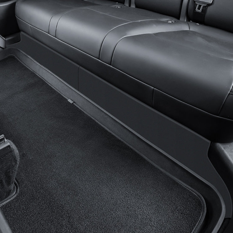 Rear seat lower protection panel along backrest bottom, dark gray with curved edge
