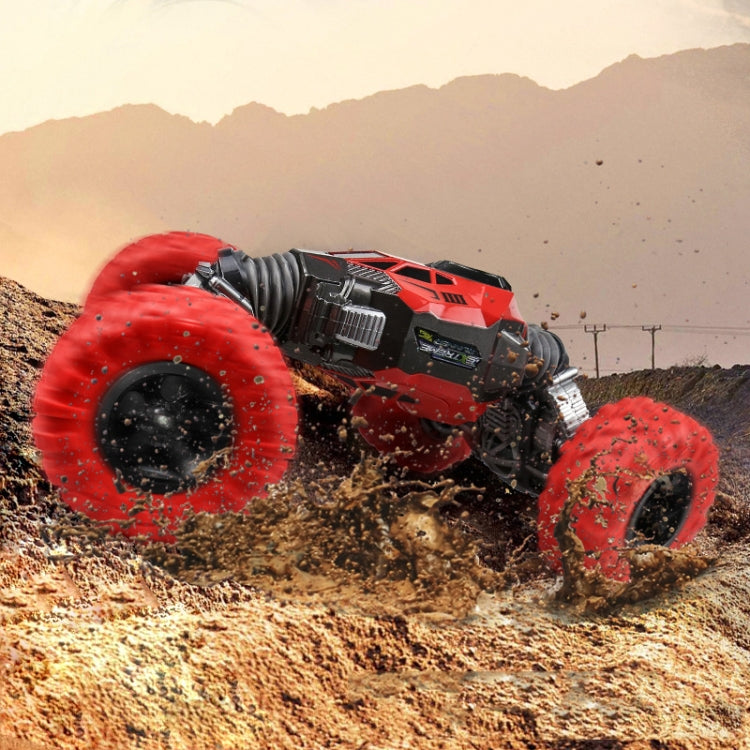Red RC off-road truck driving through dirt with four large tread tires
