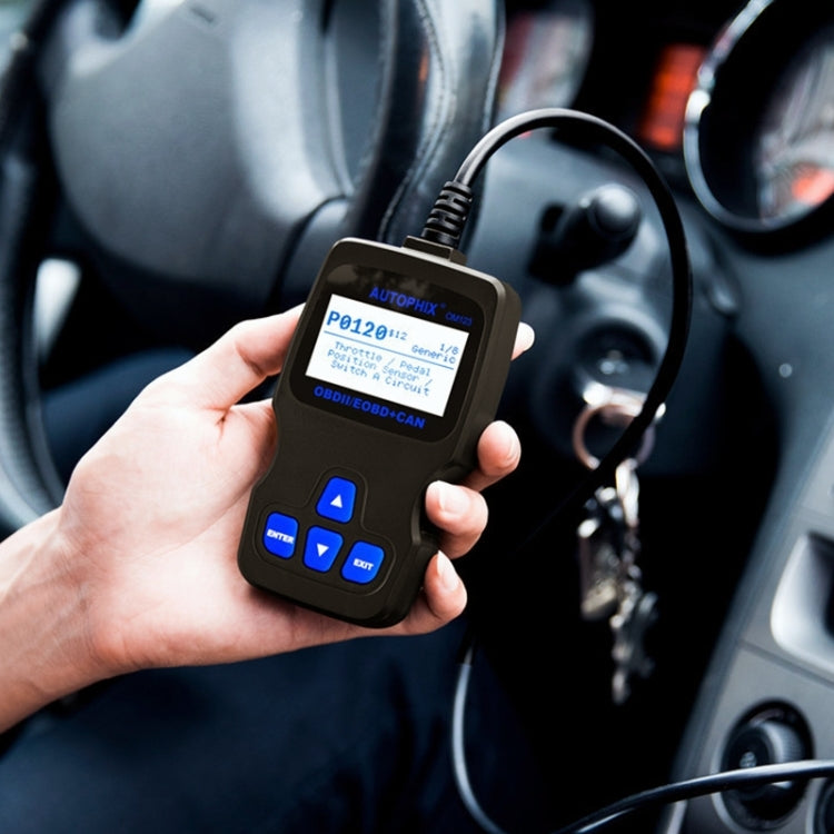 Hand holding black OBD2 code reader with attached cable near car interior