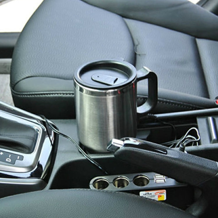 Stainless steel heated mug with black lid and handle, connected to power cord