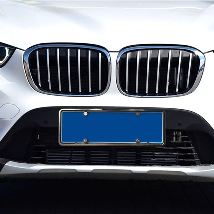 Installed silver license plate bracket frame on front of car, rectangular with holes