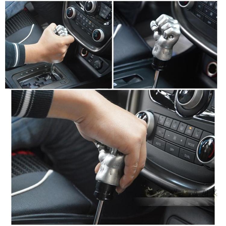 Gold fist-shaped gear shift knob installed in car interior, hand on shifter