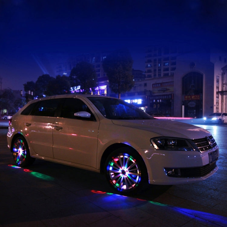 Nighttime car with solar wheel lights casting colorful rings on the wheels