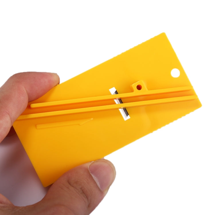 Hands holding yellow vinyl film cutter tool with two blade tracks