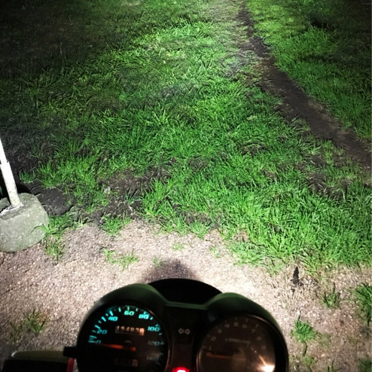 Motorcycle headlight beam illuminating grass and a dirt path at night