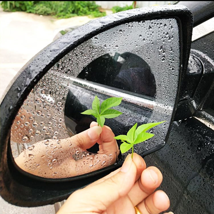 Clear anti-fog rain shield film for round car rearview mirror, being applied by hand