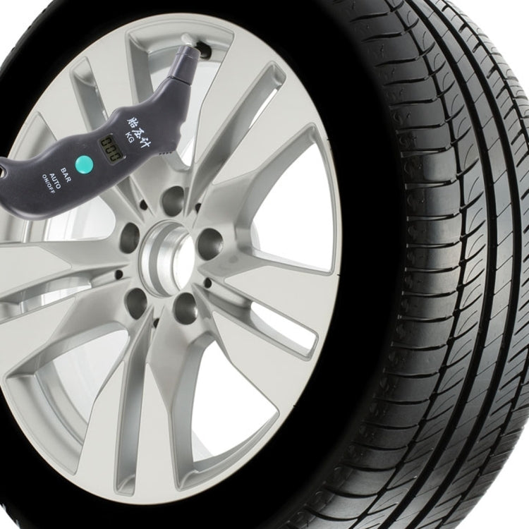 Digital tire gauge attached to car wheel tire tread, LCD facing outward