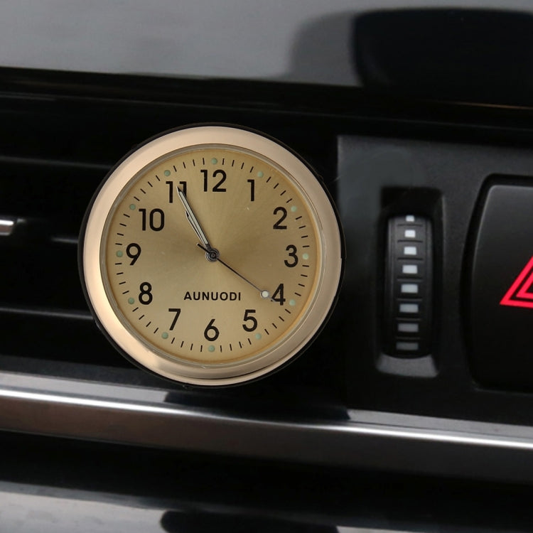 Gold dashboard air-vent clock with glowing markers on beige dial