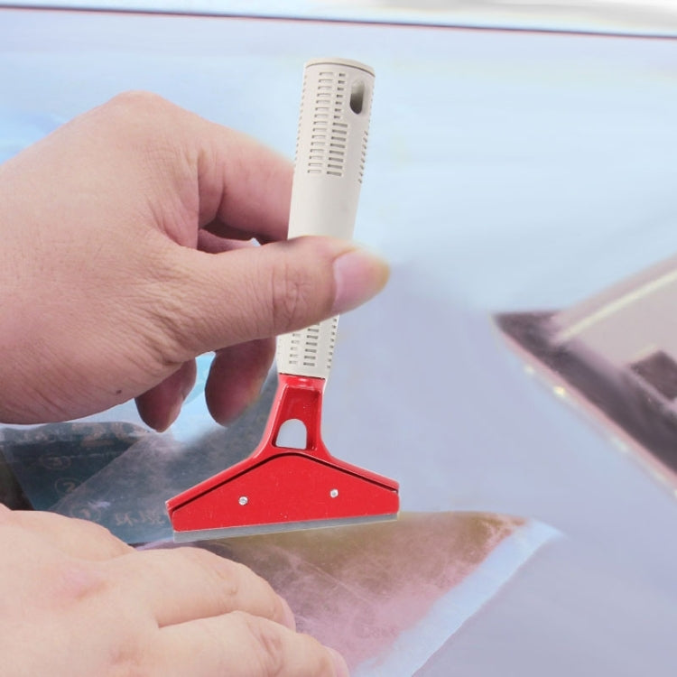 Hand holding car window film scraper against glass surface