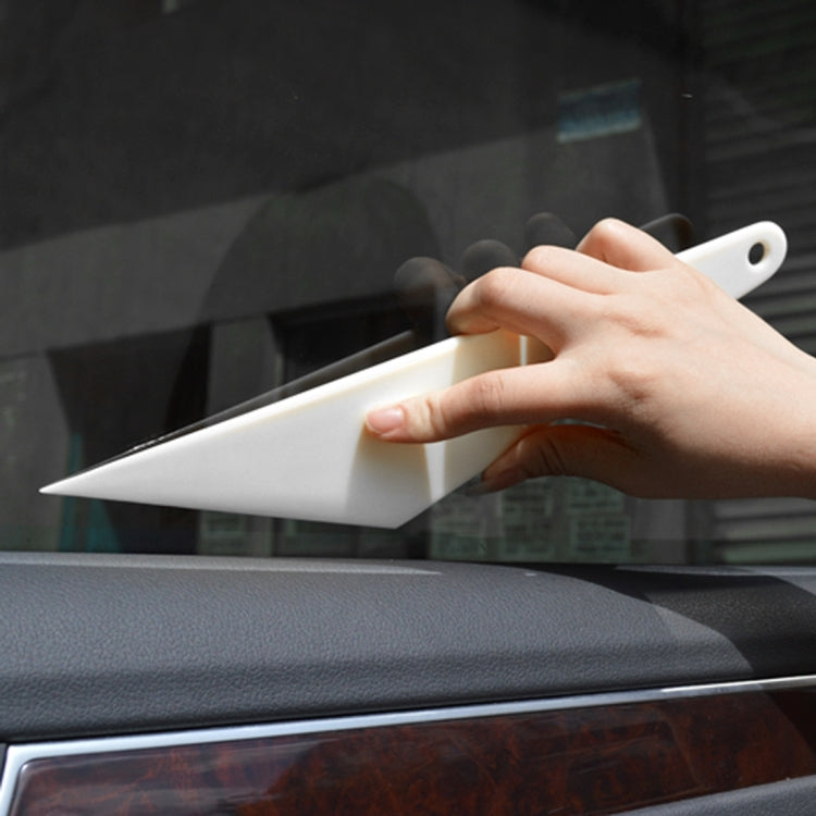 Hand holding white window film squeegee scraper tool against car glass