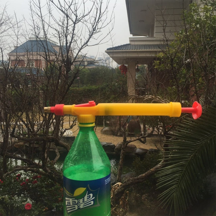 Yellow bottle sprayer attached to a green bottle, producing a fine spray over plants.
