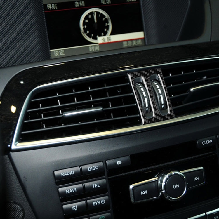 Installed carbon fiber air vent trim with two vertical oval openings and silver accent strips.