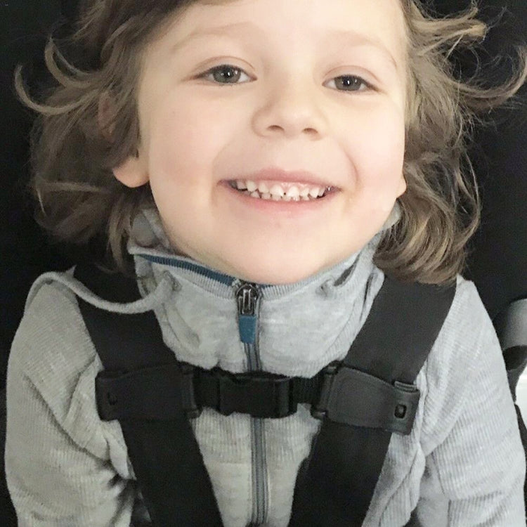 Child wearing kids car seat belt adjuster on front harness strap