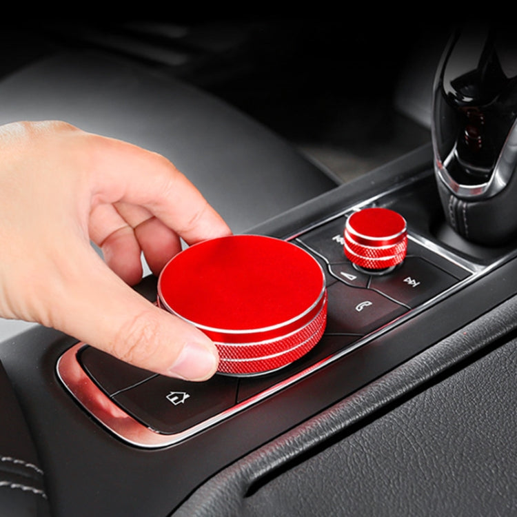 Red metal central control knob cover set with silver rings, held near car buttons