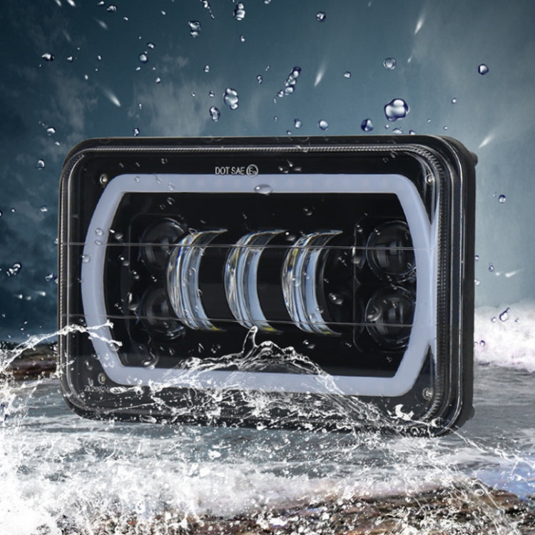 Waterproof 5-inch LED headlight with clear lens and black housing in splash