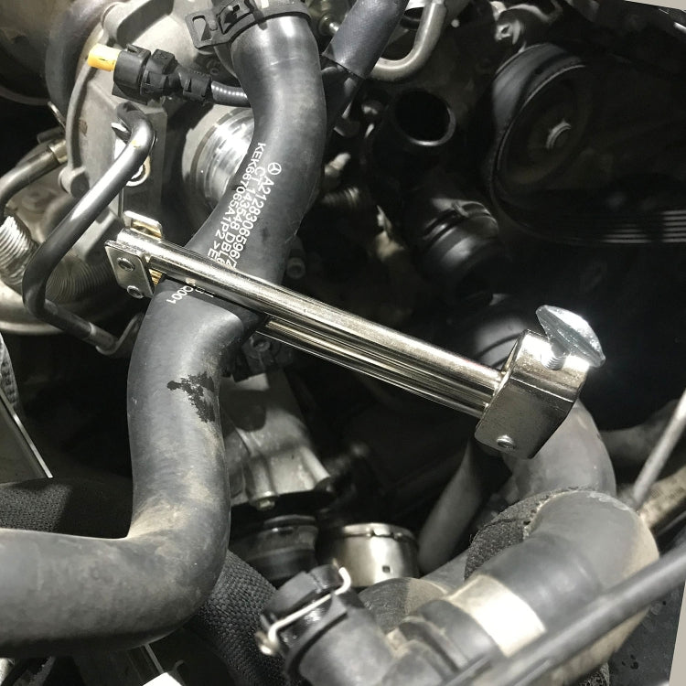 Bar-type hose clamp tool pressing against hoses in engine bay, silver metal bar