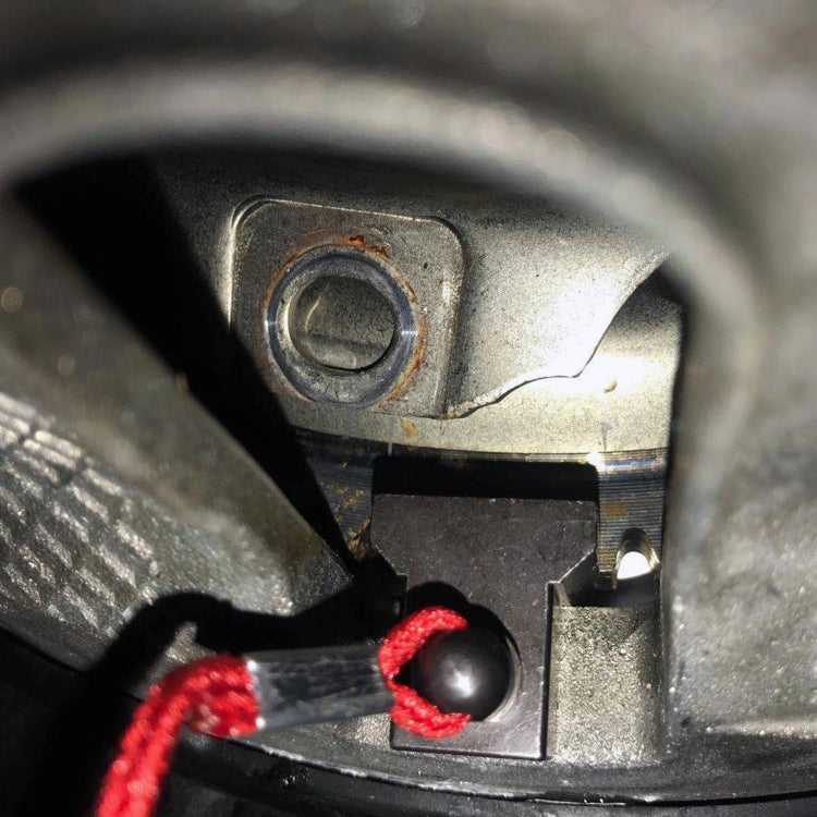 Installed engine flywheel locking tool in bay, black bracket with red cord