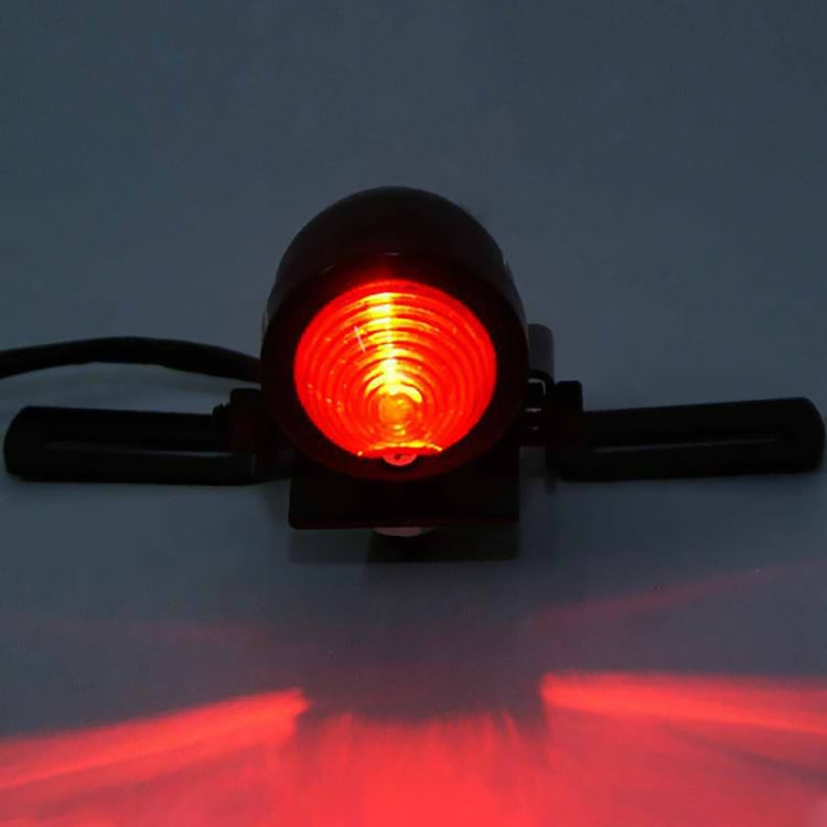 Close-up of glowing red round motorcycle brake light on black bar mount