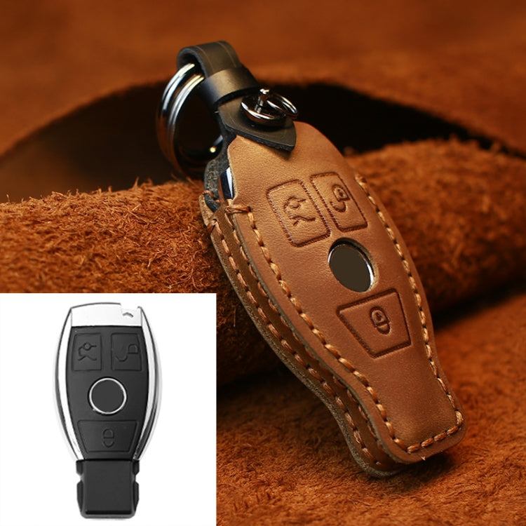 Brown leather key cover with metal ring, stitched trim, and embossed button icons