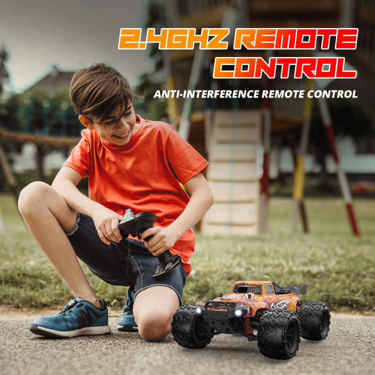 Child using a 2.4GHz remote to drive an orange 1:16 4WD RC car