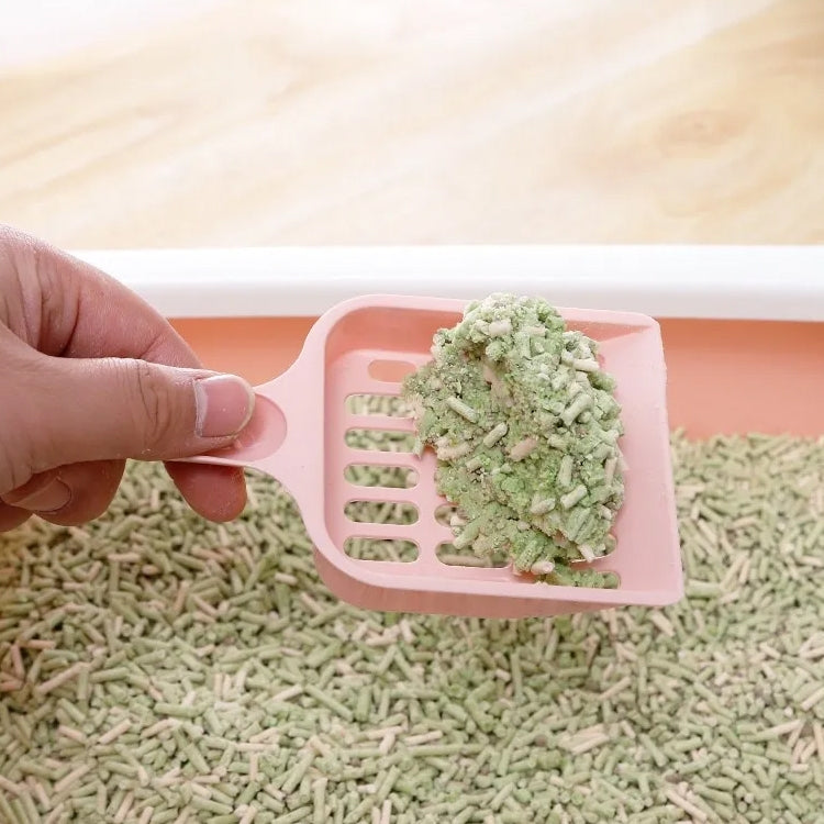 Pink cat litter scoop filled with pellets, perforated tray and long handle