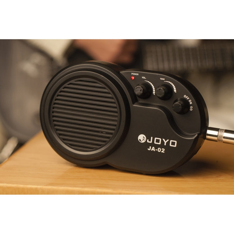 JOYO JA-02 mini guitar amp with audio cable connected and control knobs visible