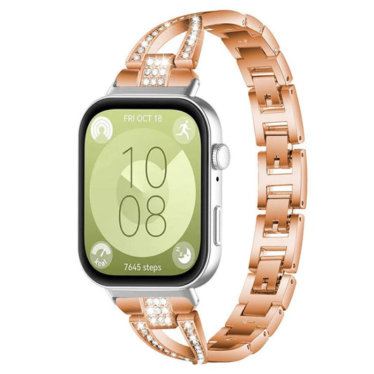 Rose gold X-shaped metal watch band with crystal accents, shown attached to a smartwatch.