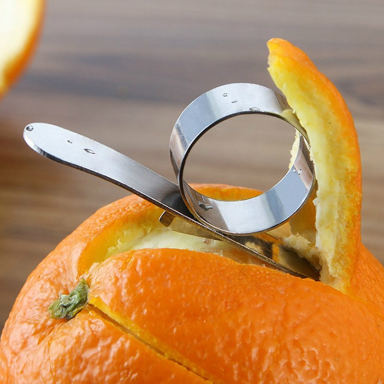 Stainless steel finger peeler cutting orange peel strips, ring holder visible