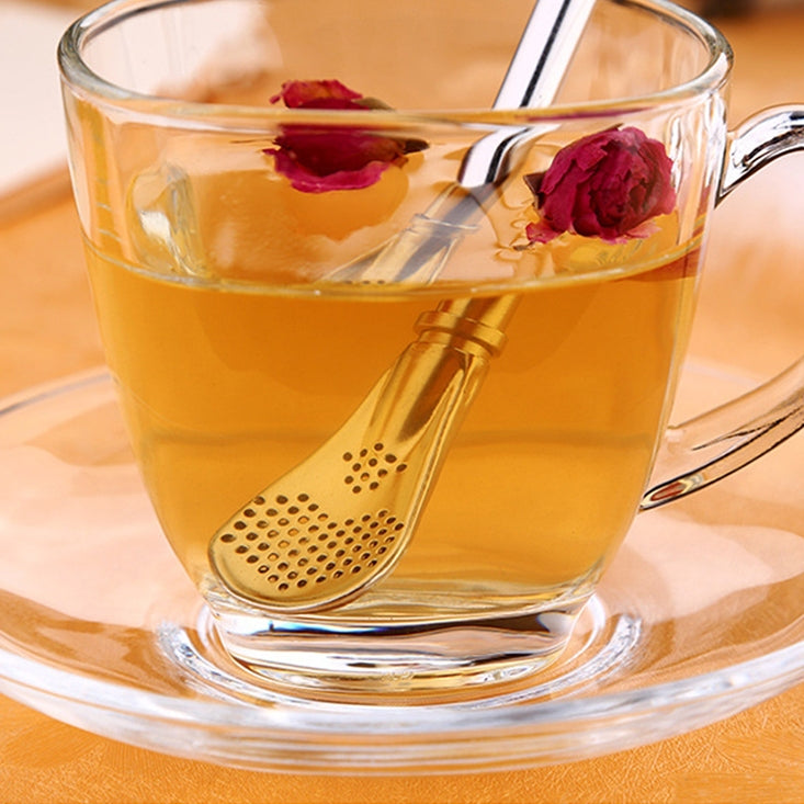Stainless steel tea infuser straw in cup of herbal tea with flower petals floating