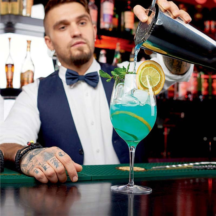 Bartender pouring from a stainless steel cocktail shaker into a glass