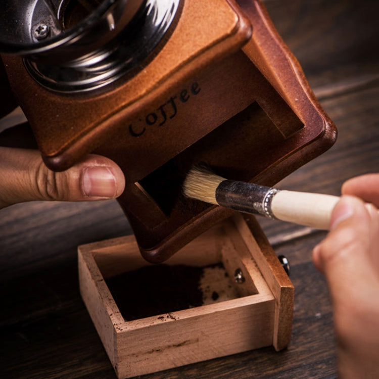 Wood-handled bristle brush cleaning inside a coffee grinder base