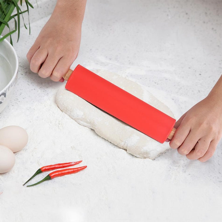 Red silicone rolling pin with wooden handles, flattening a dough log between hands.