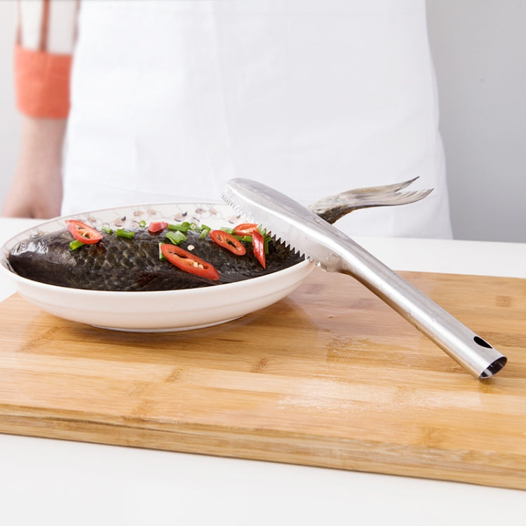 Stainless steel fish scaler knife resting on a board, ready to scrape fish scales