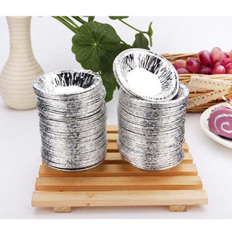 Stacked silver aluminum foil egg tart cups on a wooden base, fluted open bowls