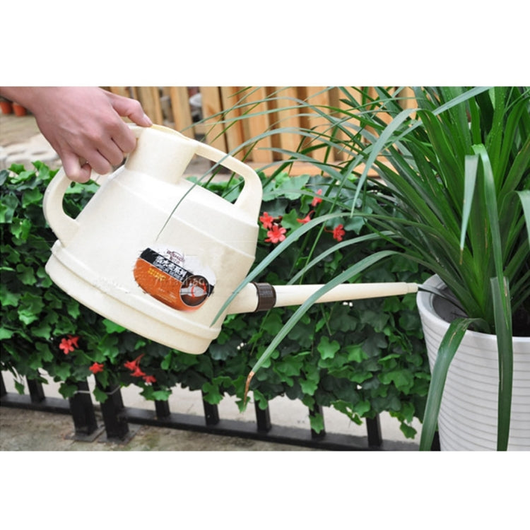Beige plastic watering can with long spout, curved handle, watering near plants