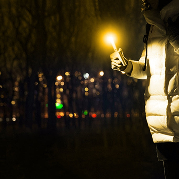 USB LED book light in hand shining warm light in dark outdoor setting