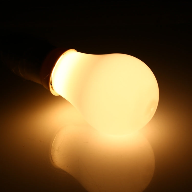 Warm white LED bulb glowing, close-up of frosted bulb shape