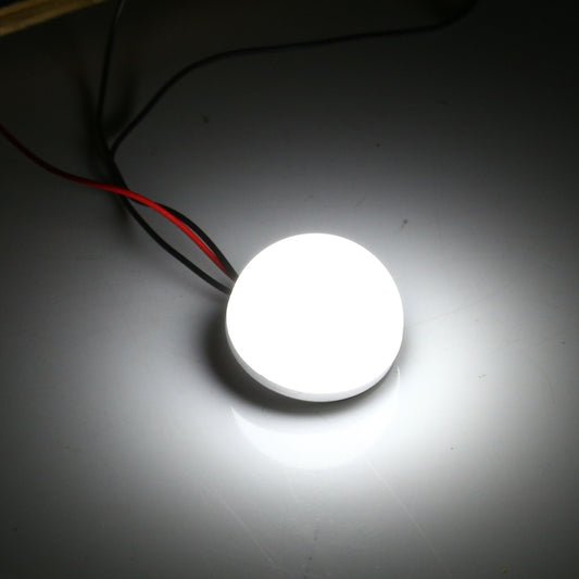 Glowing LED dome bulb with red and black electrical leads