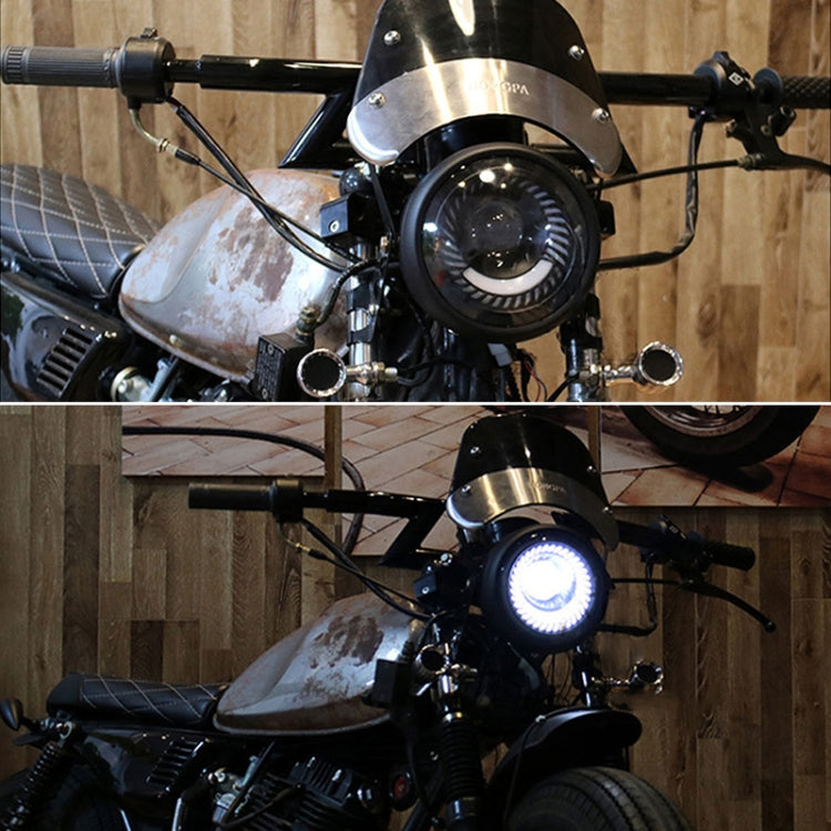 Lit round black retro motorcycle LED headlight mounted on handlebars