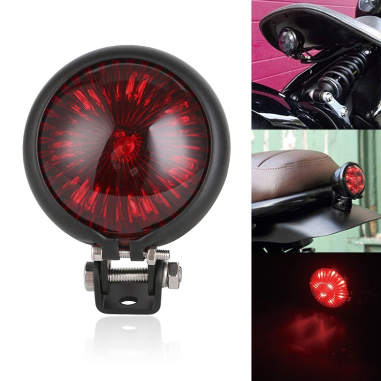 Motorcycle tail light with round red illuminated lens and black bezel, front view