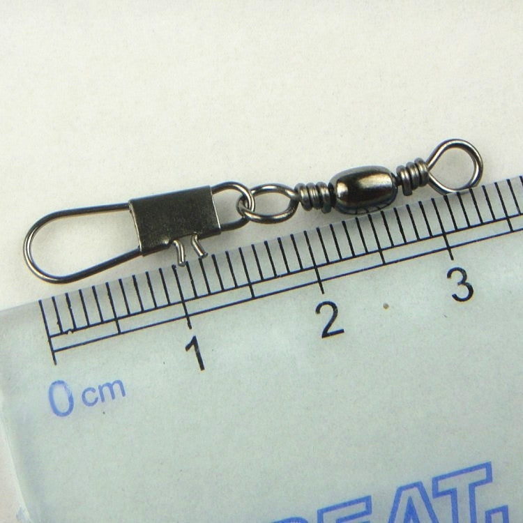 Metal fishing barrel swivel with safety snap ring beside a ruler for size