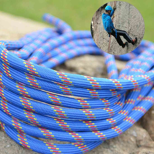 Blue climbing safety rope with multicolor woven threads, coiled on stone