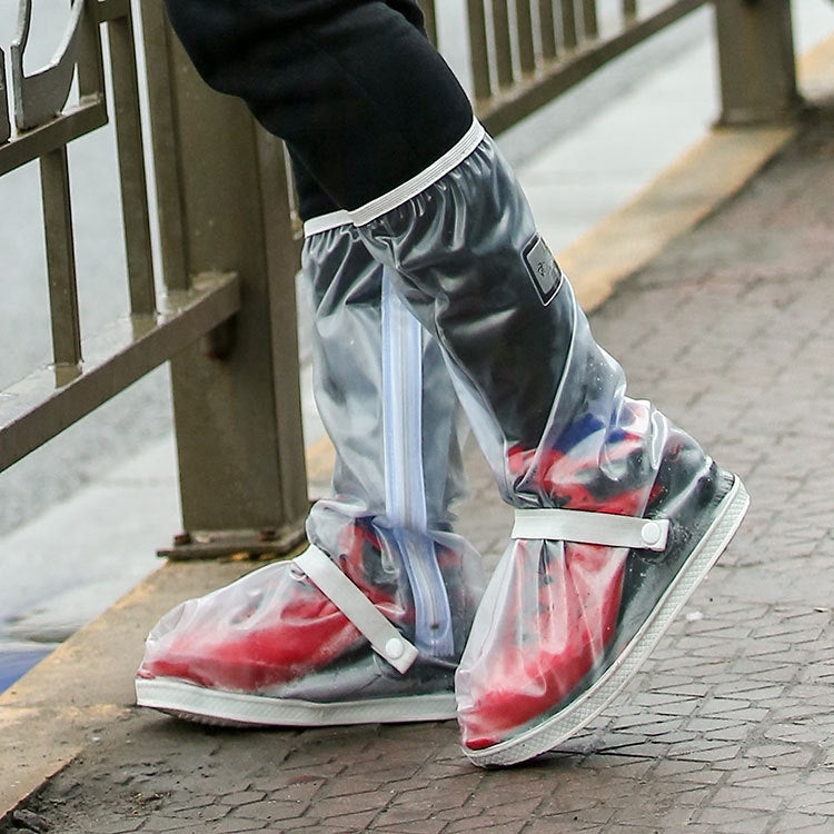 Clear rain boot covers over black shoes with red accents at the sole.