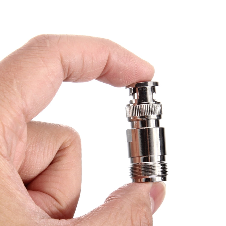 N to BNC metal RF connector held in hand, showing BNC male plug