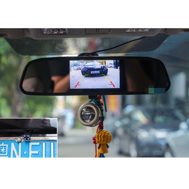 Car rear view monitor in mirror housing showing rear camera view with guidance overlays