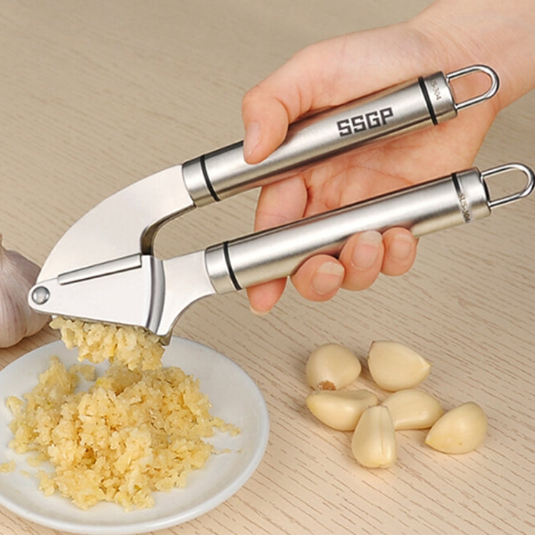 Stainless steel garlic press in use on garlic cloves and a bowl