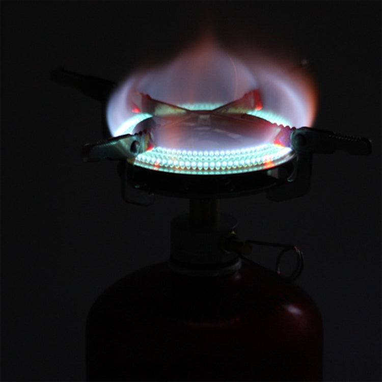 Portable gas camping stove burner lit with blue flame over the fuel canister